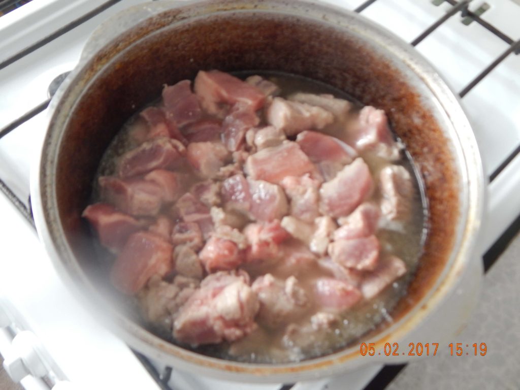 На фото: обжарка свинины для приготовления плова
